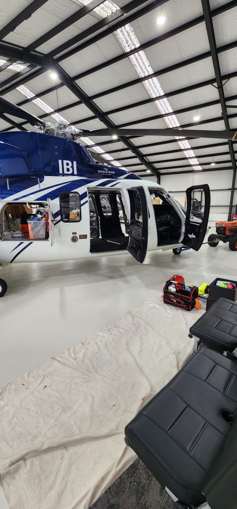 Helicopter interior detailing in progress inside a hangar, with seats removed and professional tools laid out by Skyshine Ltd.