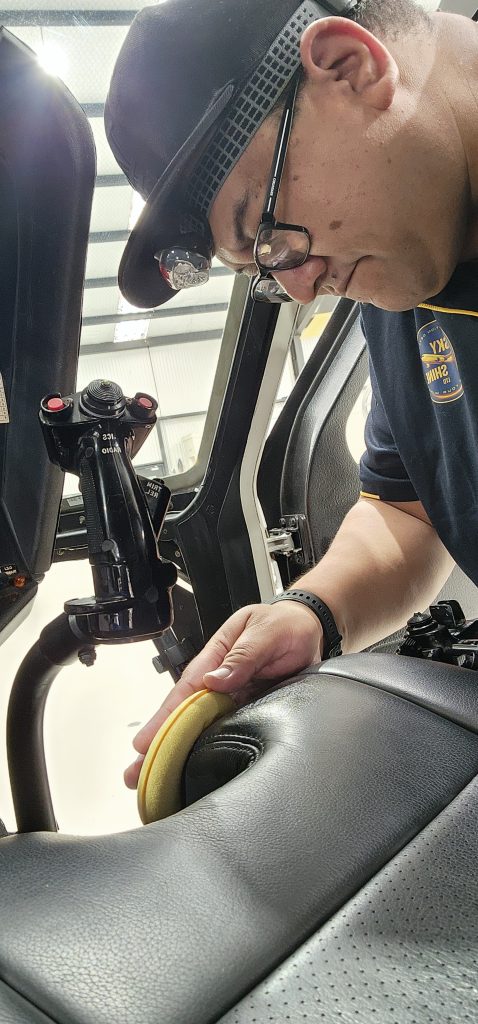 Skyshine Ltd technician carefully polishing helicopter interior leather with a detailing pad, showcasing precision and care.